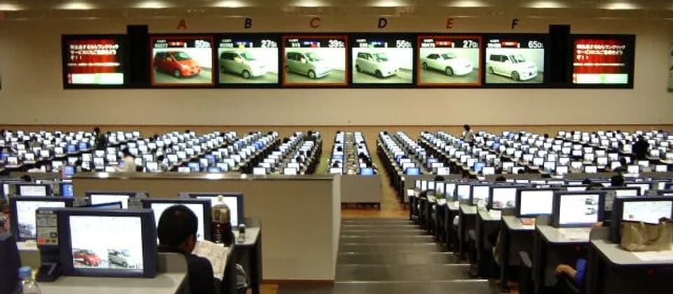 Interior of a Japanese car auction hall with bidding desks and display screens